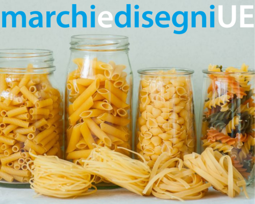 Barattoli di vetro con diversi formati di pasta secca, tra cui penne, conchiglie e fusilli tricolori, e nidi di tagliatelle in primo piano.